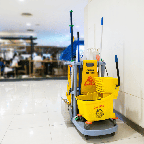 Wózek serwisowy do sprzątania obiektów – mop, wiadra i znak „wet floor” w galerii handlowej