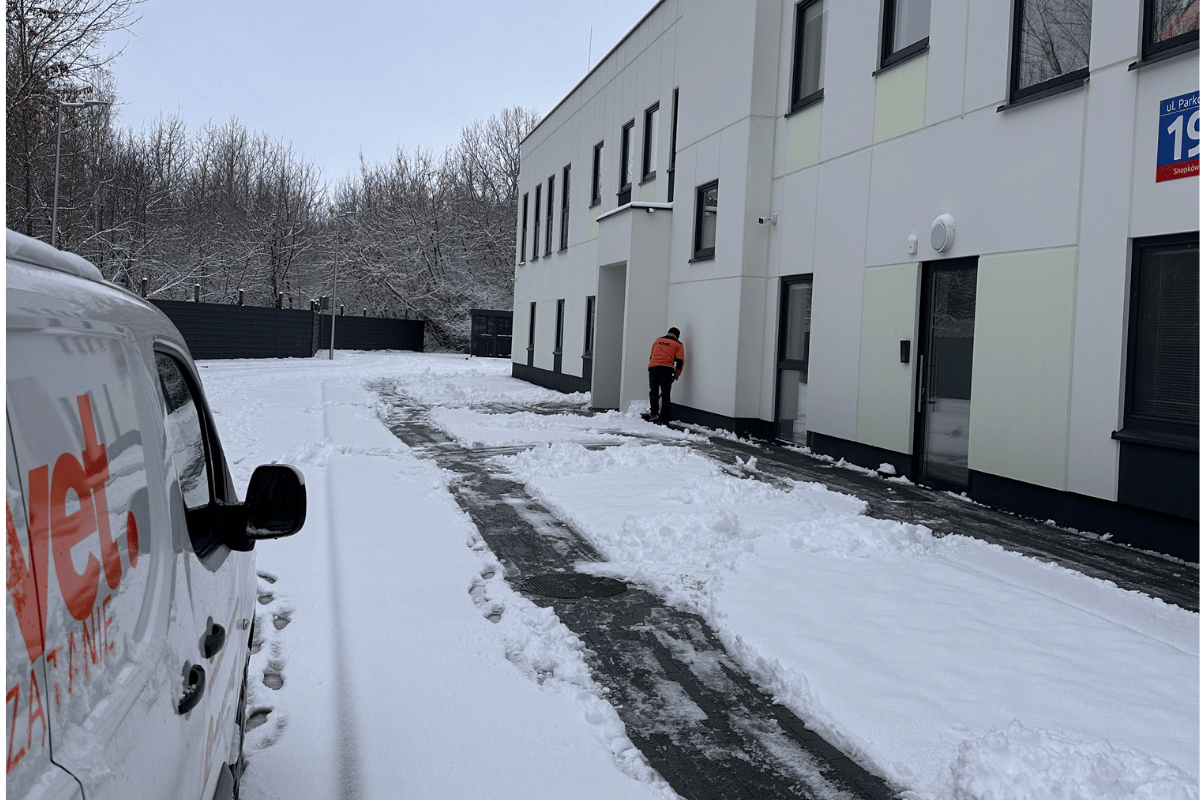 Pracownik Velvet Sprzątanie odśnieżający chodnik przy obiekcie firmowym w Lublinie