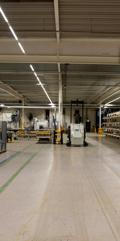 Hala przemysłowa z szeroką posadzką i liniami komunikacyjnymi – przestrzeń produkcyjna w trakcie pracy, przygotowana do sprzątania maszynowego