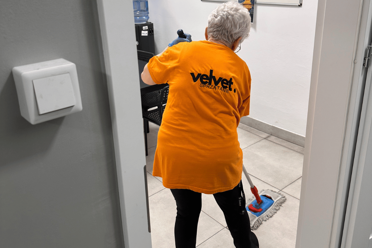 Pracownica Velvet Sprzątanie myje podłogę mopem w korytarzu biurowym