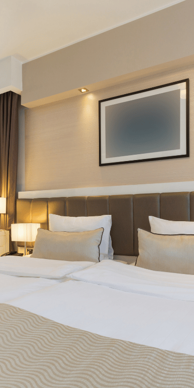 Sprzątanie hoteli Lublin – świeżo przygotowany pokój hotelowy z pościelą i oświetleniem przy łóżku
