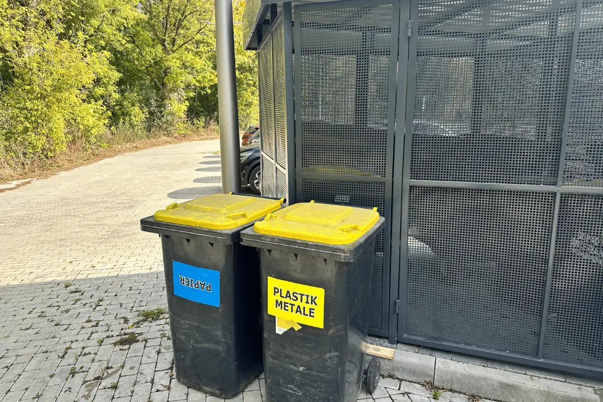 Segregowane pojemniki na odpady w zadbanej altanie śmietnikowej na terenie osiedla
