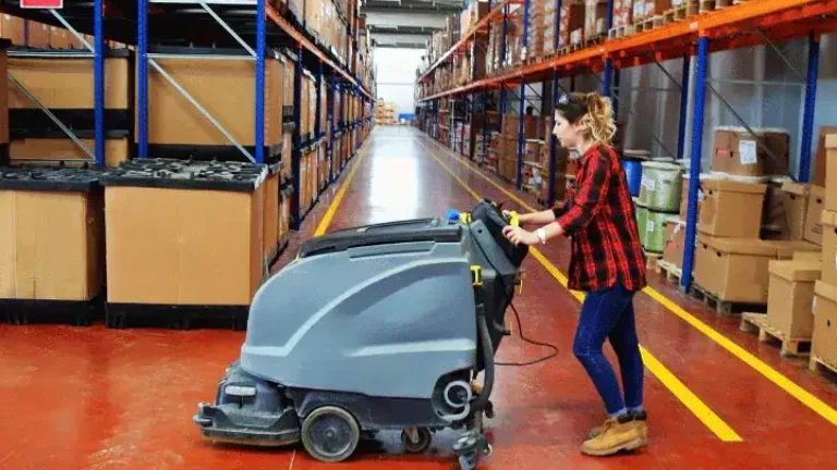 Pracownica myjąca posadzkę maszynowo w hali magazynowej w Lublinie