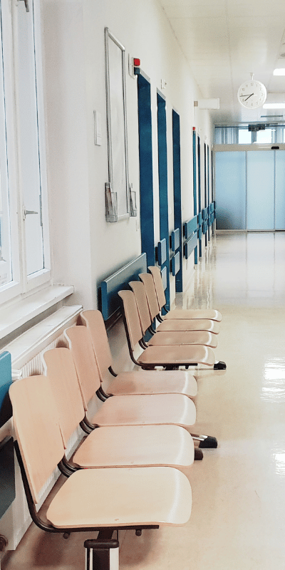 Korytarz przychodni z rzędem krzeseł w poczekalni – czyste części wspólne placówki medycznej.