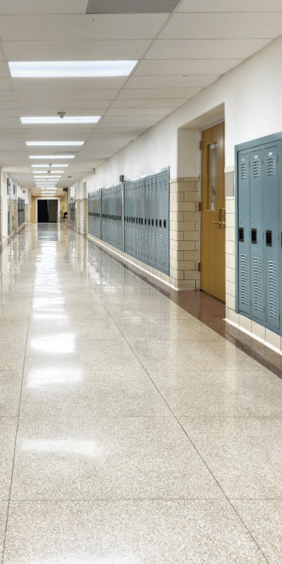 Korytarz szkoły z rzędami szafek — wypolerowana podłoga po serwisie sprzątającym.