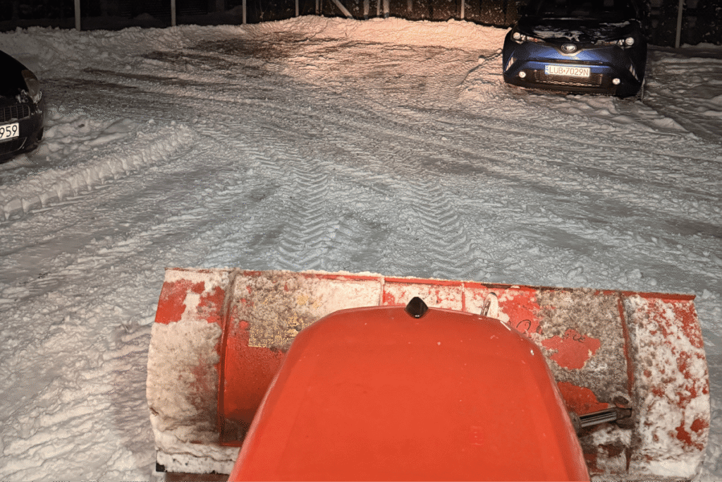 Odśnieżanie parkingu wspólnoty – odgarnianie śniegu pługiem na osiedlu nocą