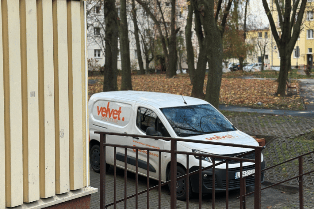 Samochód firmowy Velvet Sprzątanie zaparkowany przy budynku – dojazd na realizację
