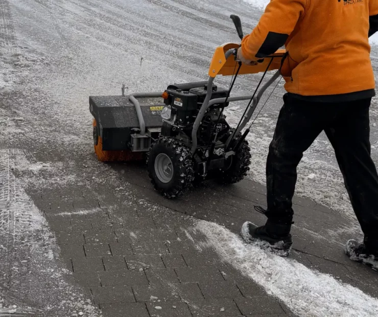Mechaniczne odśnieżanie chodnika i drogi osiedlowej przy użyciu zamiatarki do śniegu