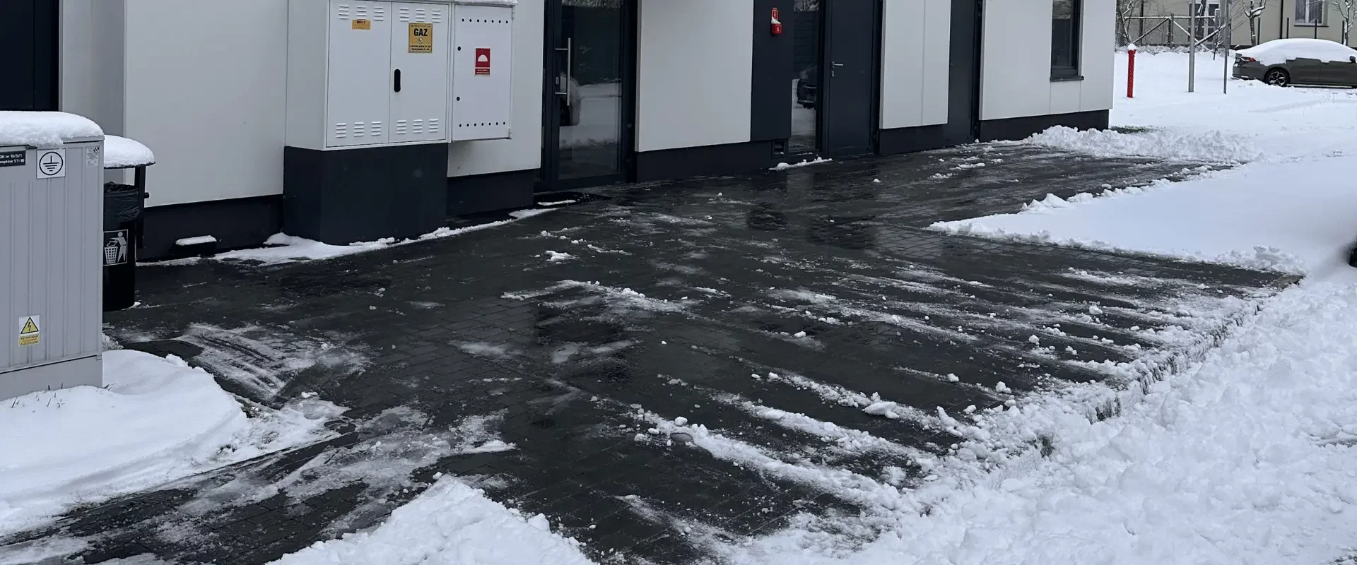 Odśnieżony teren przy wejściach do budynku po zimowych opadach śniegu