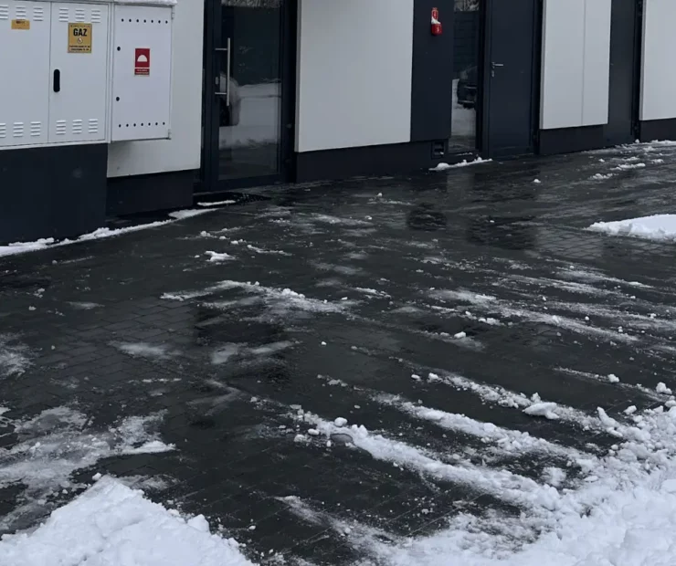 Odśnieżony teren przy wejściach do budynku po zimowych opadach śniegu