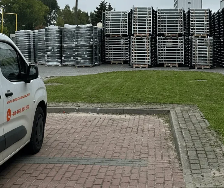 Samochód serwisowy Velvet Sprzątanie zaparkowany przy terenie zewnętrznym obiektu z utwardzonym parkingiem, trawnikiem i strefą magazynową w tle