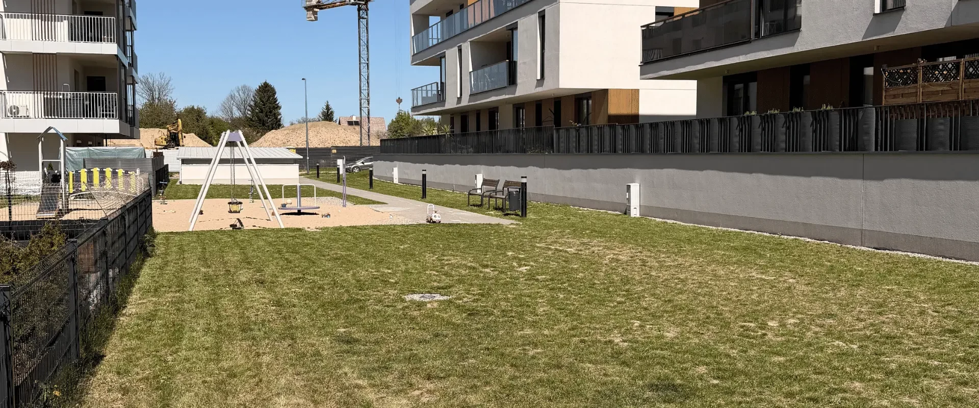 Skoszony trawnik i plac zabaw na terenie nowoczesnego osiedla mieszkaniowego