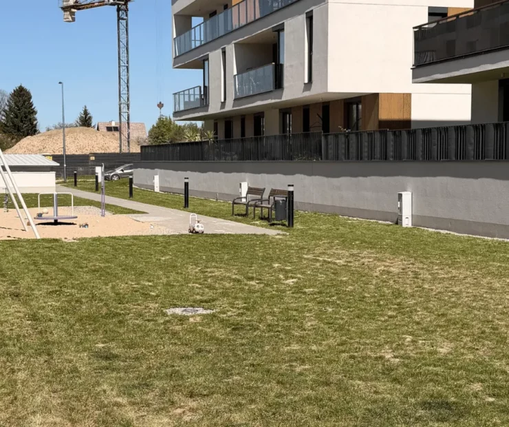 Teren zewnętrzny wspólnoty mieszkaniowej po koszeniu trawy przy placu zabaw i budynkach mieszkalnych