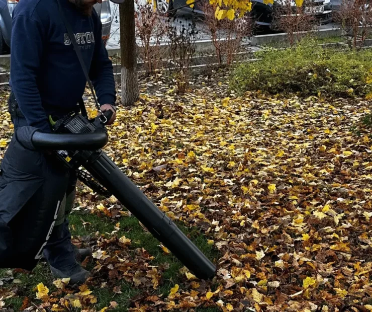 Usuwanie jesiennych liści dmuchawą na terenie osiedla mieszkaniowego