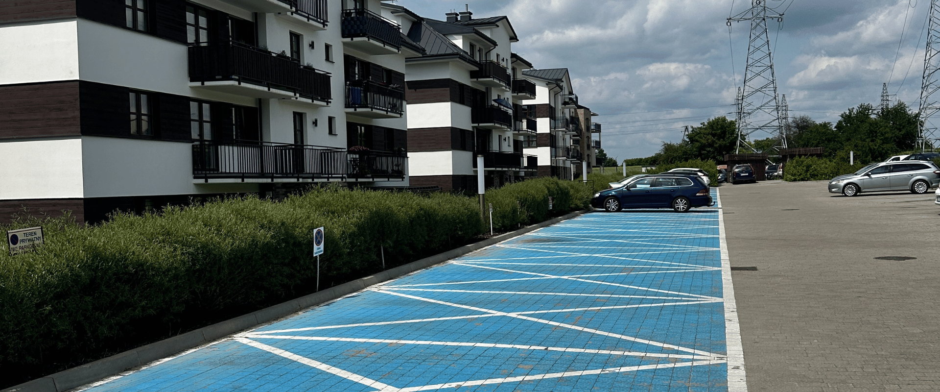 Zimowe utrzymanie osiedla mieszkaniowego, odśnieżona droga wewnętrzna i parking podczas opadów śniegu