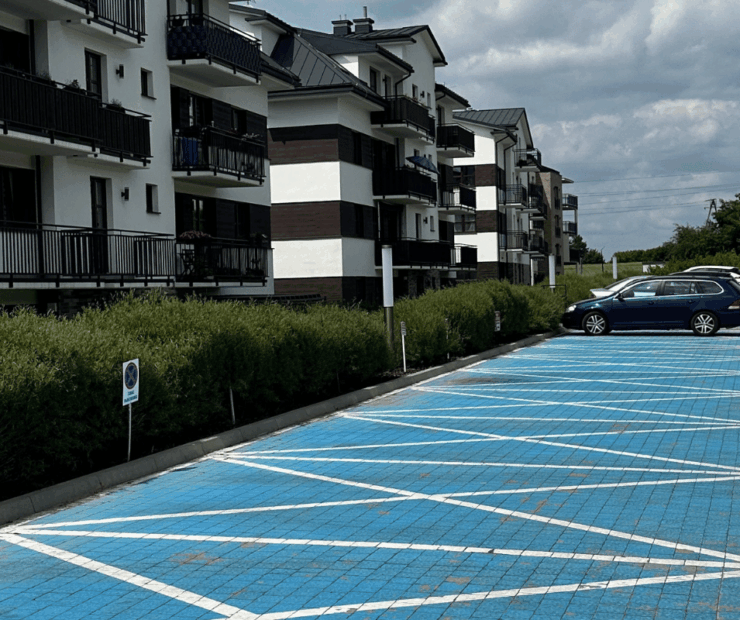 Zimowe utrzymanie osiedla mieszkaniowego, odśnieżona droga wewnętrzna i parking podczas opadów śniegu