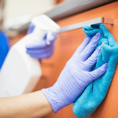 Dezynfekcja uchwytu w przychodni – rękawiczki i ściereczka z preparatem